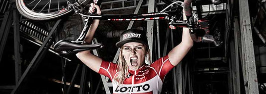 Puck Moonen die wielrenfiets op de kop vasthoudt